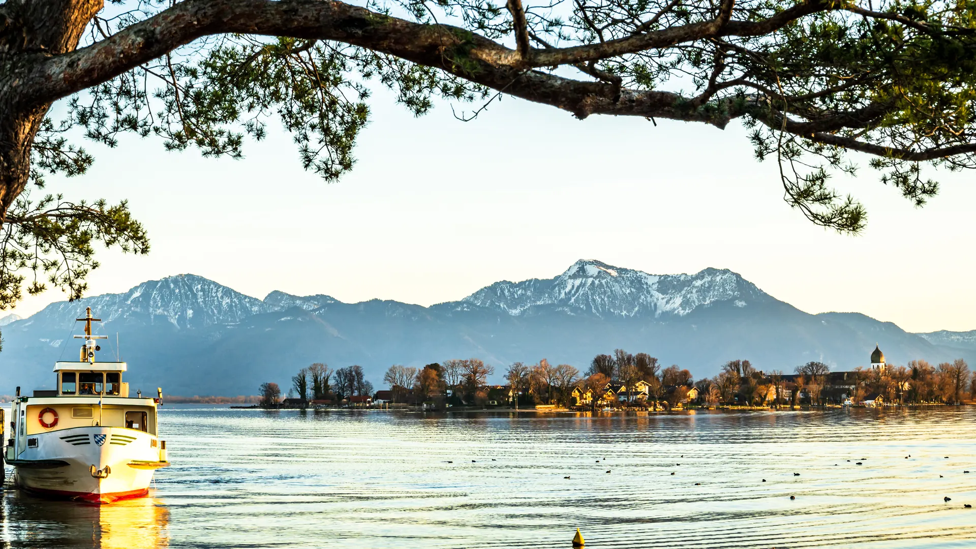 Schiff am Anleger eines Sees mit Bergpanorama im Abendlicht