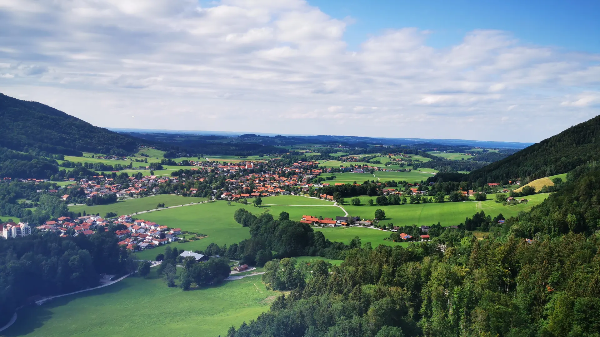Ort in einem grünen Tal mit bewaldeten Hängen im Voralpenland